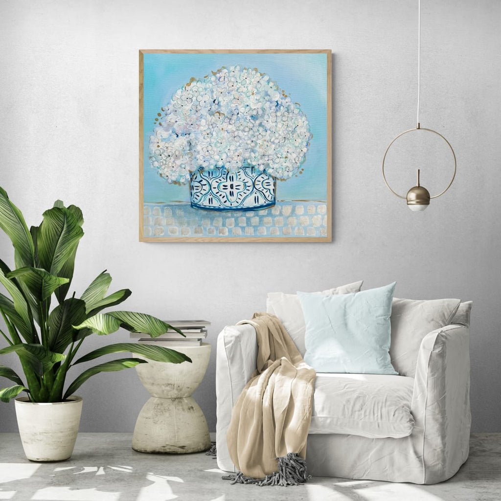 Living room with a gray armchair, plant, and wall art of a floral arrangement.