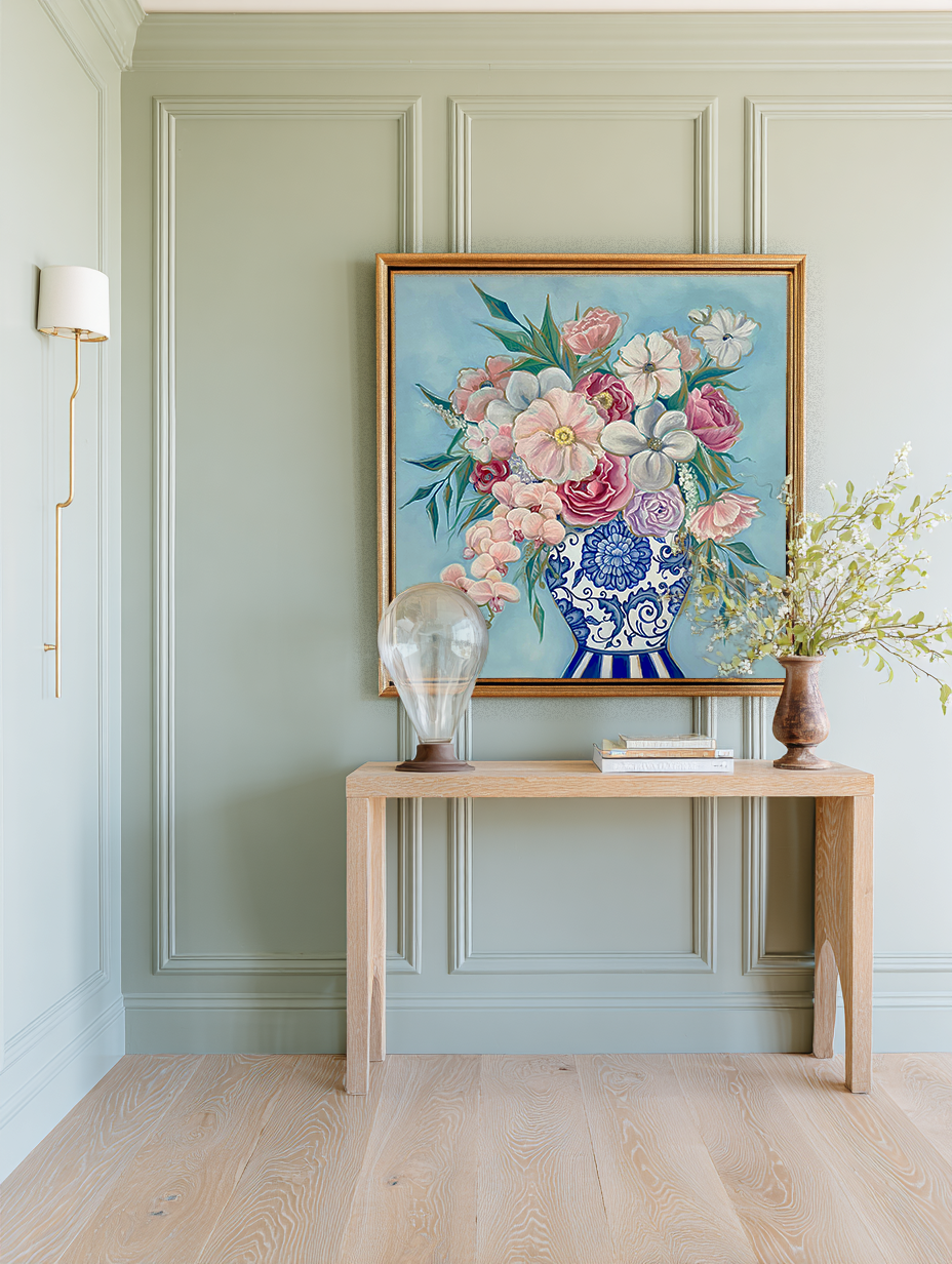 Floral painting on a wall above a wooden console table with decorative items.