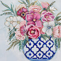 Colorful floral arrangement in a blue and white patterned vase on a light background