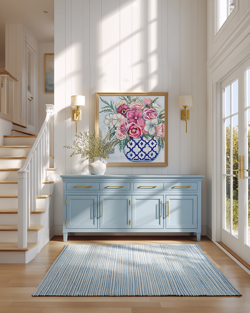 Foyer with blue cabinet, floral artwork, and light wood floors