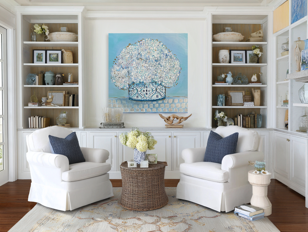 Living room with white armchairs, a coffee table, and decorative items on shelves.