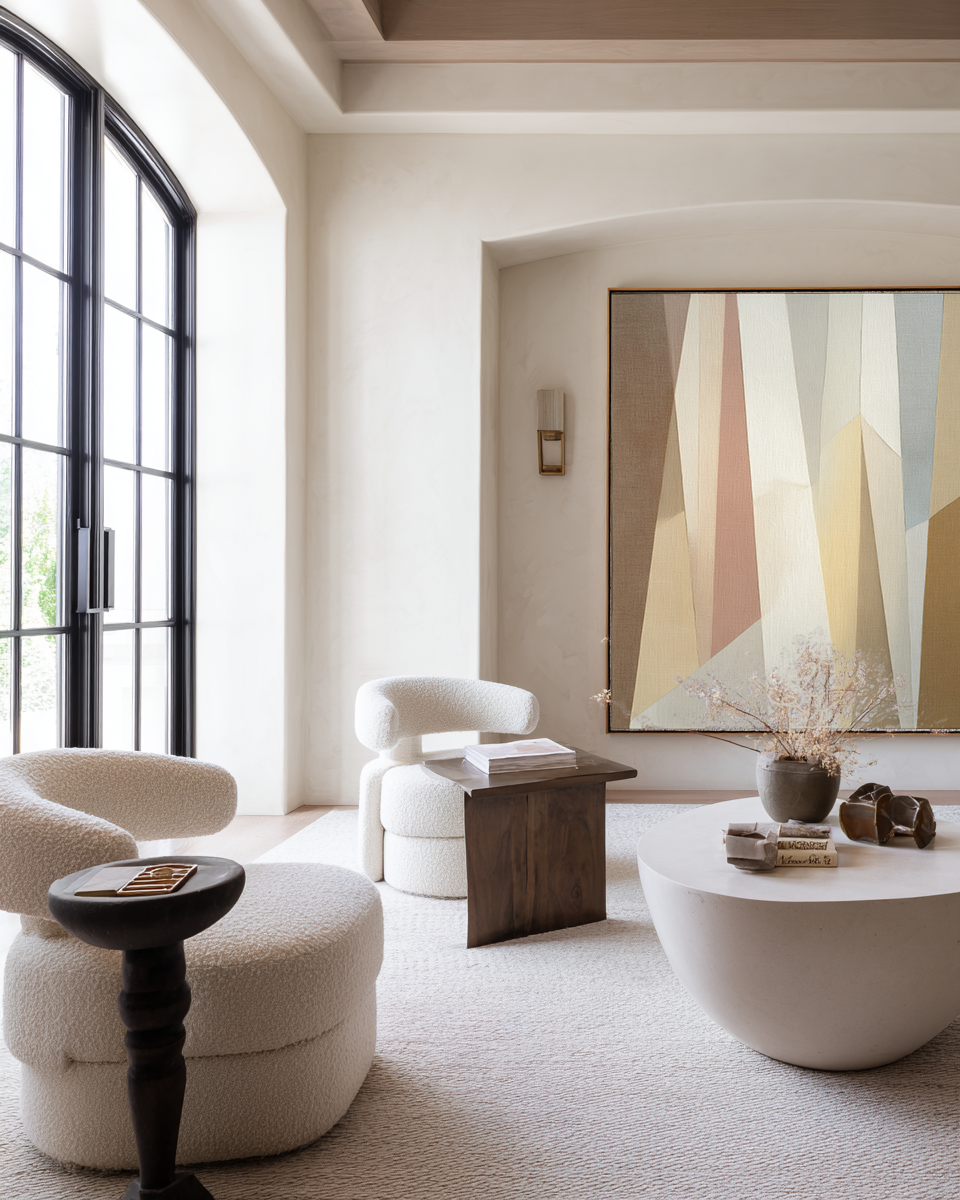 Modern living room with white furniture, abstract painting, and decorative items.