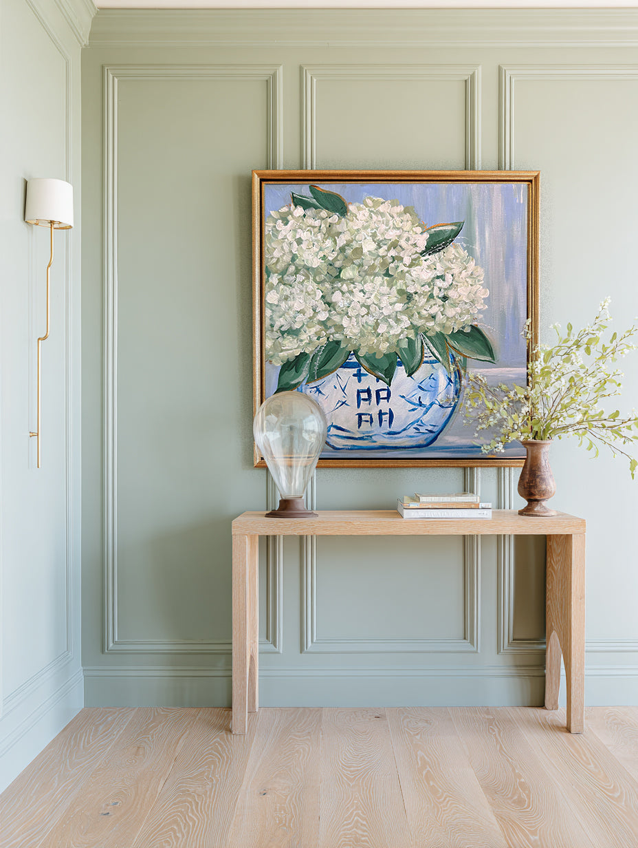 Room interior with a painting of white flowers, a console table, and decorative items.